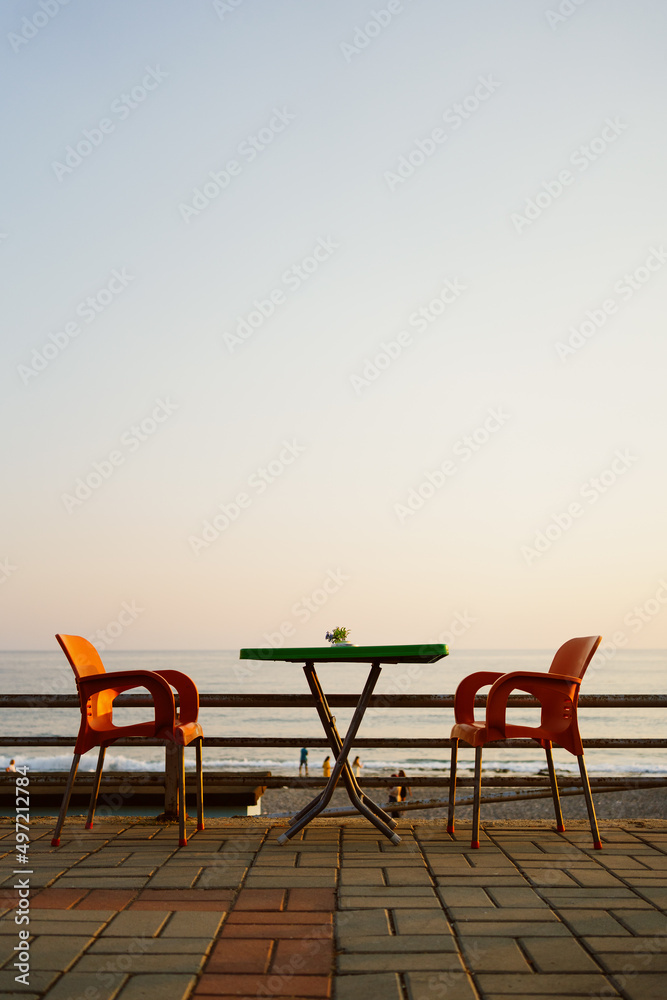 Fototapeta premium Orange plastic chairs with furniture at the seaside terrace with sky on background