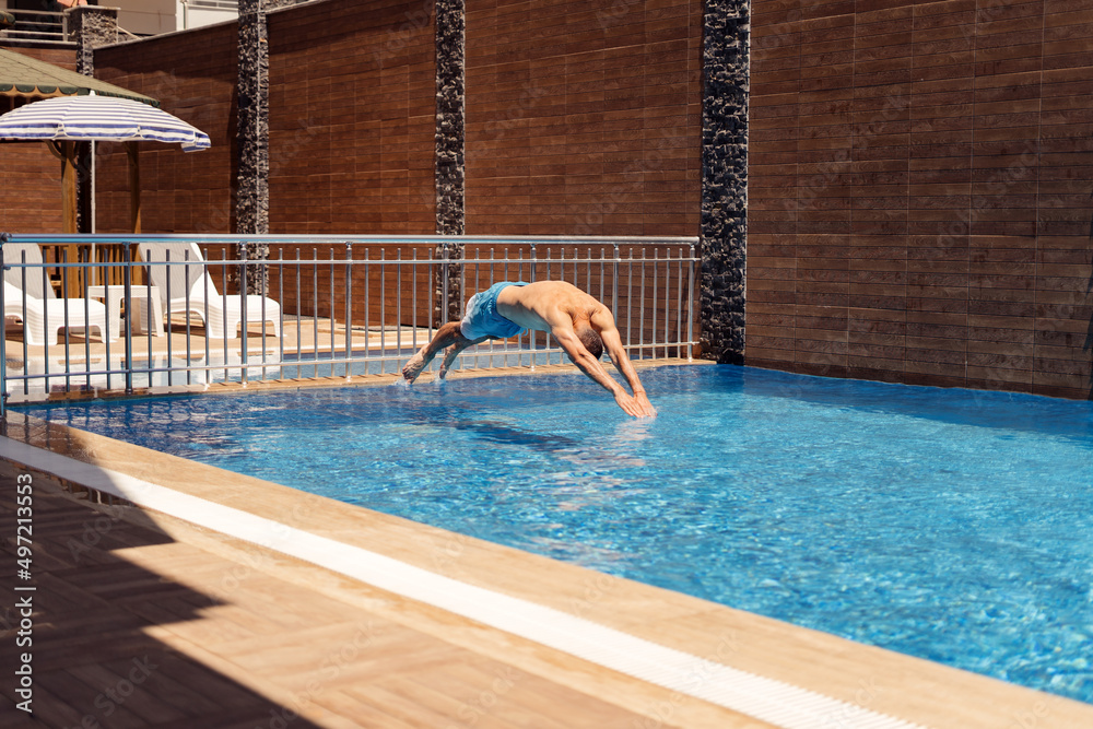 Man jumping in a beautiful, clean, house swimming pool on a relaxed sunny day