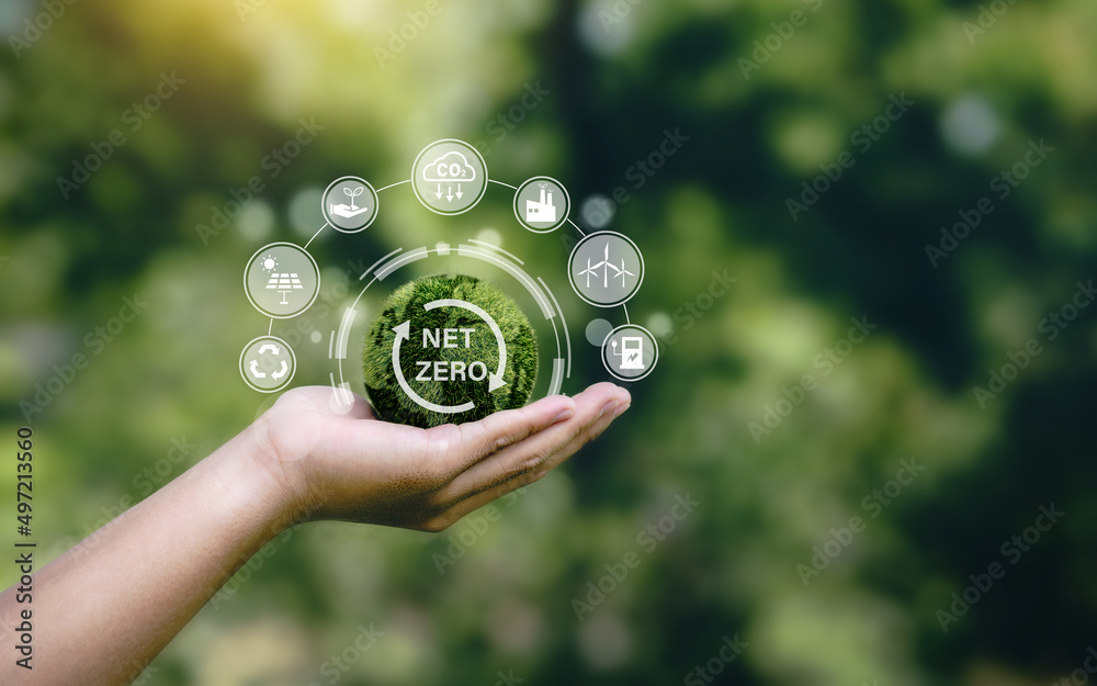 Net zero icon and carbon neutral concept in the hand for net zero greenhouse gas emissions target Climate neutral long term strategy on a green background. Net zero icon and carbon neutral concept in the hand for net zero greenhouse gas emissions target Climate neutral long term strategy on a green background.