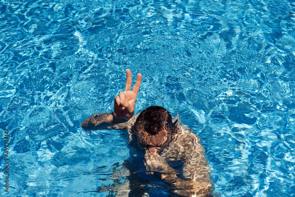 Man chilling under water in pool and showing signs ok with his hand