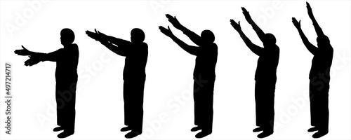  The person raises both hands simultaneously and smoothly up. Sport. Warm-up for older people. The movement of two hands from below and to the top. An elderly woman is standing half sideways.