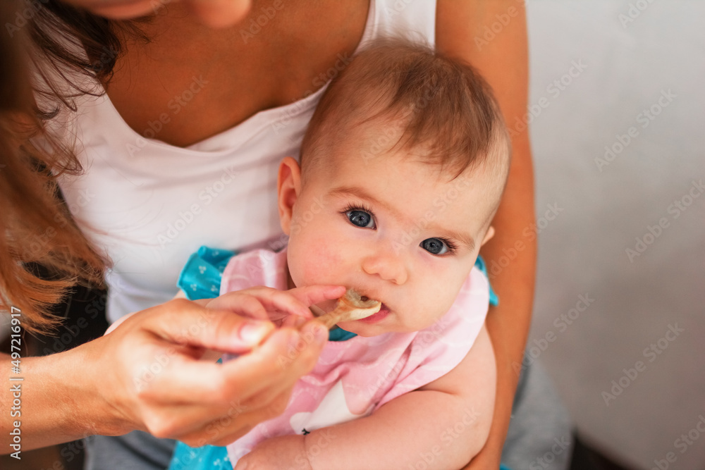 Mother feeding cute baby girl vegetable puree from a spoon. Healthy eating nutrition for little kids Mother feeding cute baby girl vegetable puree from a spoon. Healthy eating nutrition for little kids
