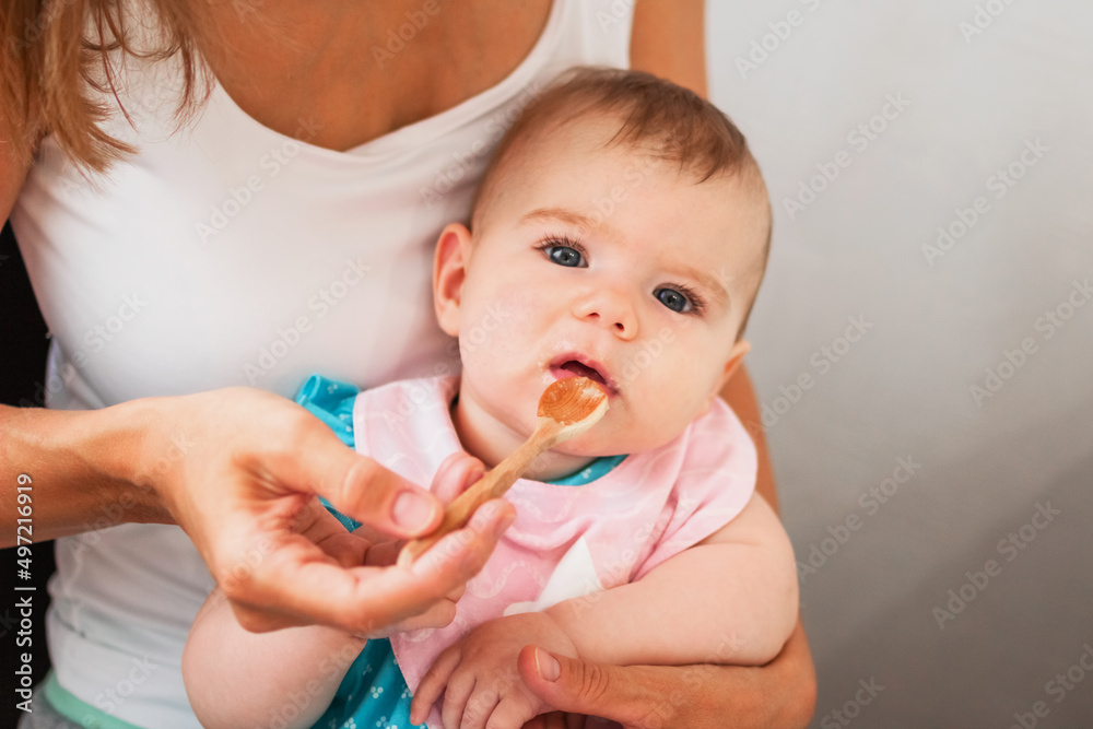 Mother feeding cute baby girl vegetable puree from a spoon. Healthy eating nutrition for little kids Mother feeding cute baby girl vegetable puree from a spoon. Healthy eating nutrition for little kids