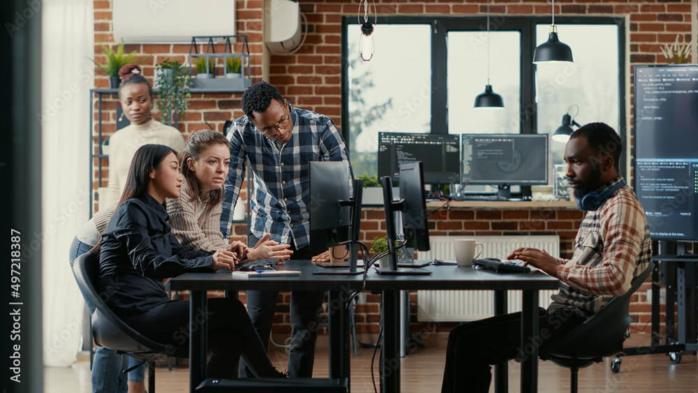 Junior developers collaborating on group project compiling algorithm asking senior programer for help while intern joins the discussion. Software engineers brainstorming ideas looking at screens.