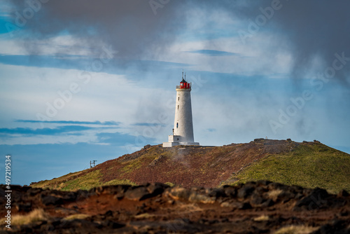 Lighthouse over the volcanic landscape and dark cloudy sky