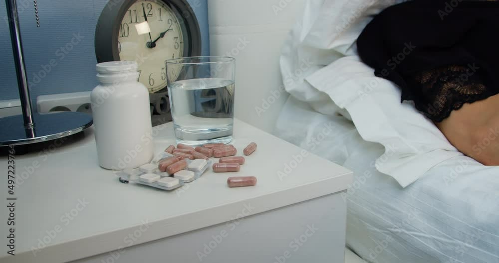 Closeup woman hand takes tablets and pills from the table