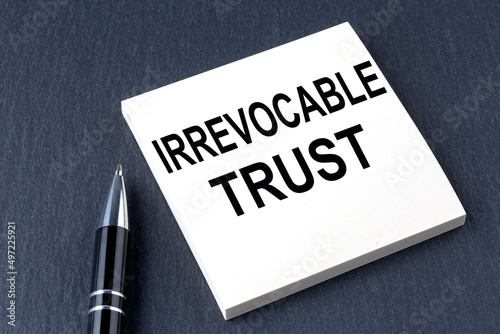 IRREVOCABLE TRUST text on the sticker with pen on the black background photo