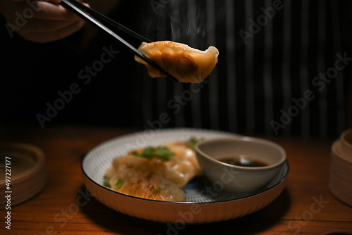 Female hands using chopsticks with Chinese fried dumpling or gyoza