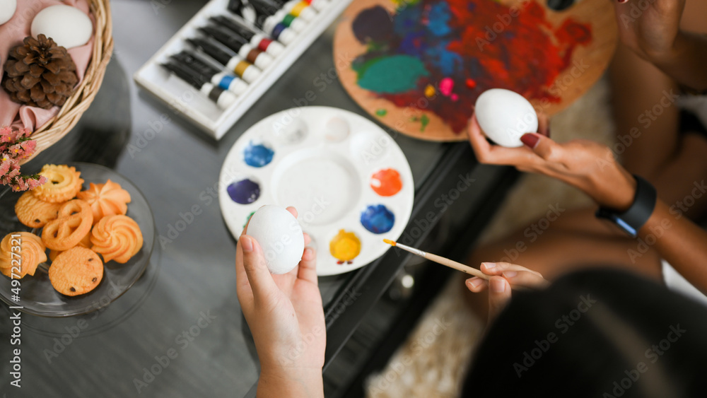 Fototapeta premium Close-up and above view image, Mom and daughter painting an Easter egg
