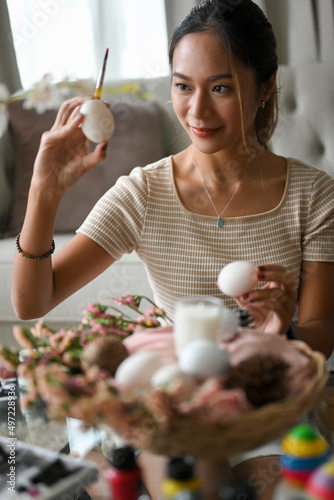 Woman with an Easter egg, painting a colourful colour on Easter egg.