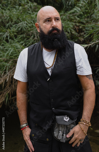 Portrait shot of a spiritual bearded man with bald head who is standing in a middle of the nature observing the environment