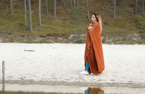 beautiful young woman covered with blanket with on the beach