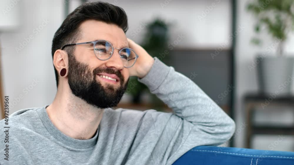 Joyful handsome guy resting on comfortable couch smiling dreaming memories planning positive emotion Joyful handsome guy resting on comfortable couch smiling dreaming memories planning positive emotion
