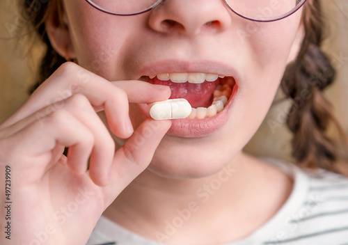 A child holds a white tablet and opens the mouth. Medicines and synthetic vitamins. The concept of drug selection. Treatment for children.