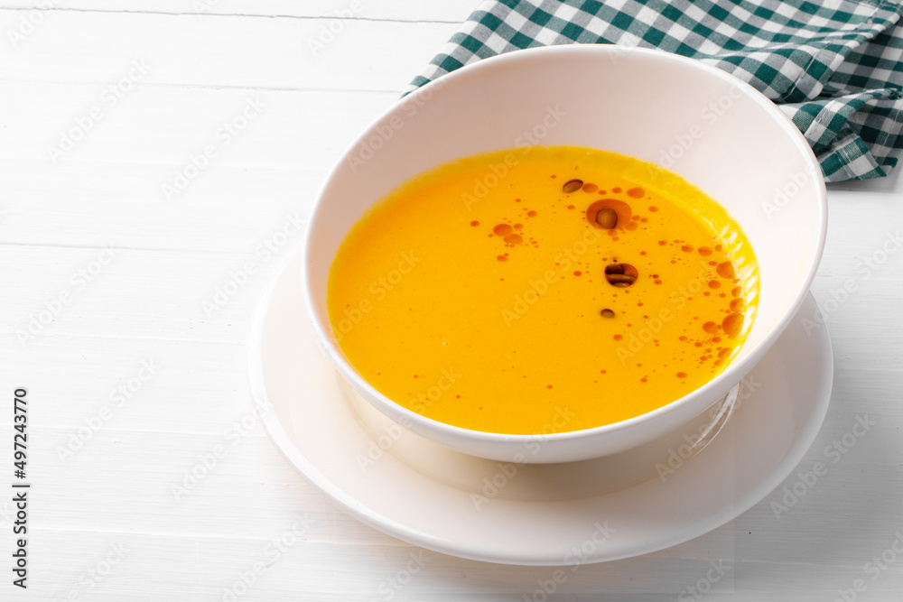 Pumpkin creamy soup served in bowl on white wooden background Pumpkin creamy soup served in bowl on white wooden background