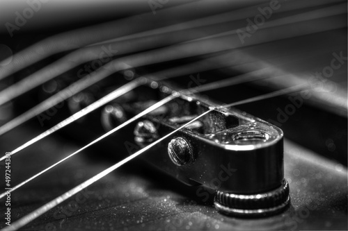 Grayscale closeup of the guitar strings and the bridge photo