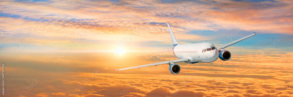 Wide panoramic view, banner of a flying passenger plane on a picturesque sunset sky, travel trip.