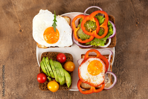 Healthy breakfast with various of sandwiches and toasts on the white plate. Wooden background. Top view.