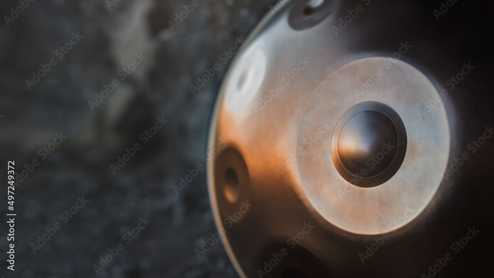 A close-up view of a musical instrument called a handpan, also known as a hang or pantam. Copy space, shallow depth of field. A close-up view of a musical instrument called a handpan, also known as a hang or pantam. Copy space, shallow depth of field.