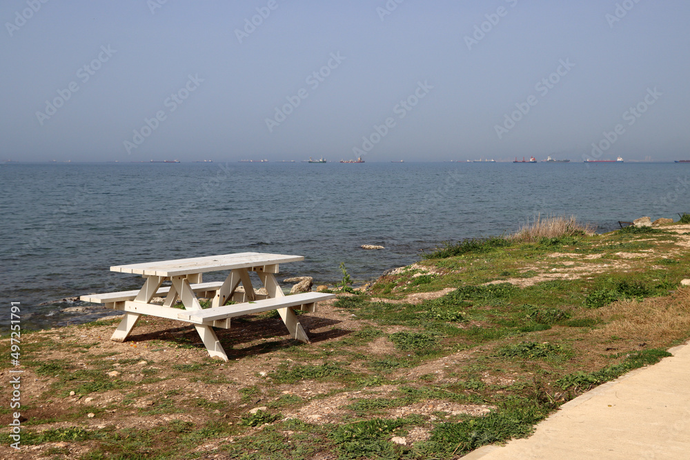 Wooden table and benches on a beach. Tranquil sea, blue sky, no people. 