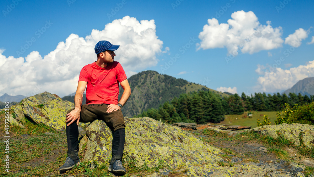 Man sits on a rock in front of a mountain