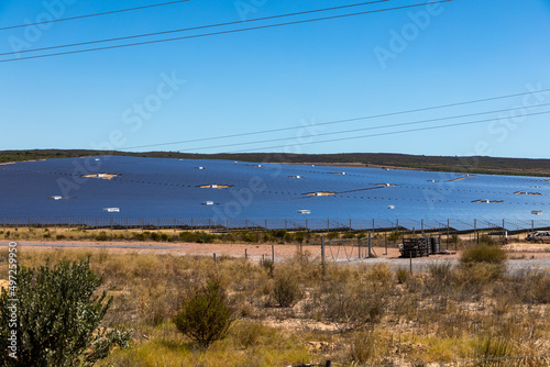 Semi desert area with a large selection of photovoltaic solar panels in the backgound. Clear blue sky