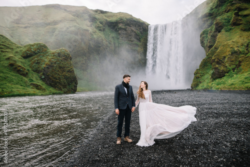 Stylish Bride and groom on elopement near Skogafoss waterfall. Iceland wedding
 photo