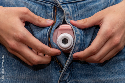 фотографія A man holds a spy camera in the fly of his denim pants