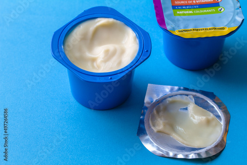 Blue plastic containers with yogurt isolated on blue background - fun creamy yogurt image and selective focus