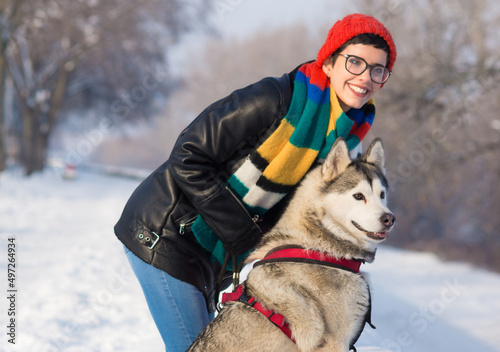 Young woman walking her husky dog in winter snow