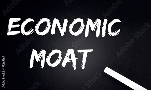 ECONOMIC MOAT Text on Black Chalkboard with a piece of chalk