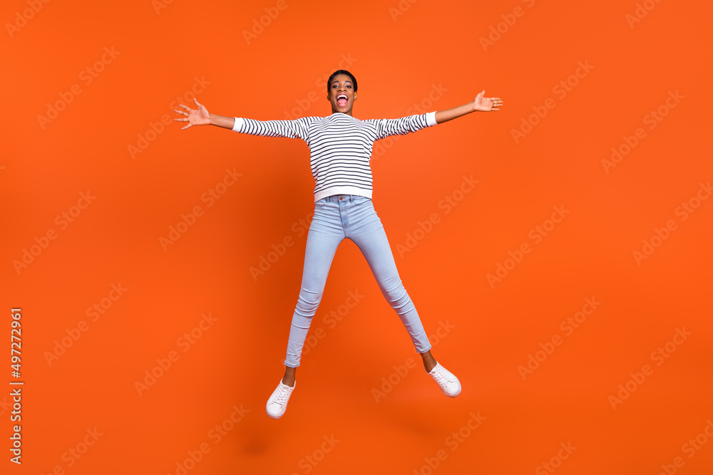 Full length body size view of attractive cheerful girl jumping having fun isolated over vivid orange color background