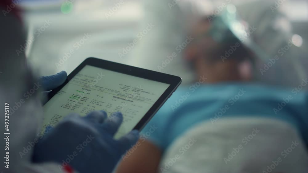 Doctor holding tablet screen checking patient medical history in ward closeup.