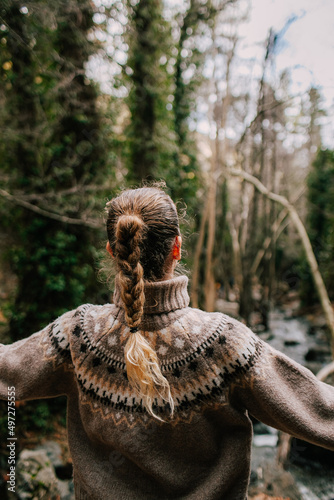 Girl with a pigtail in a sweater from the back, a walk in the forest in nature