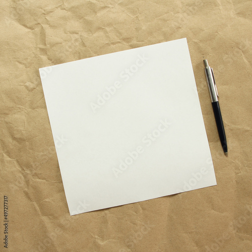 Square white empty sheet of paper with pen on a beige craft paper. Concept of analysis, study, attentive work. Stock photo with empty place for your text and design. Square image shape.