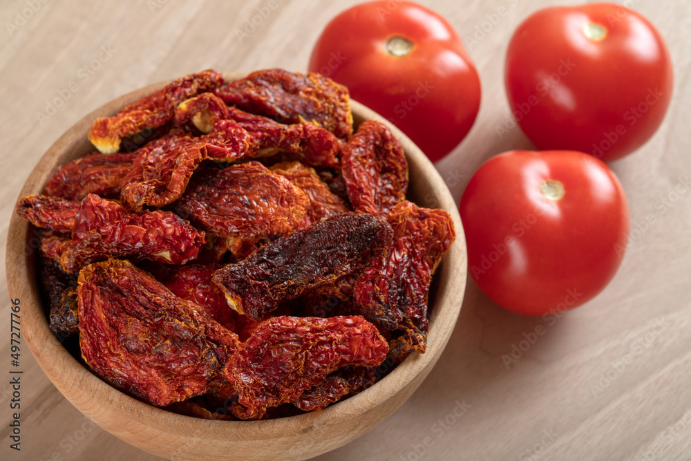 Obraz premium Fresh tomatoes and sun-dried tomatoes on wooden background