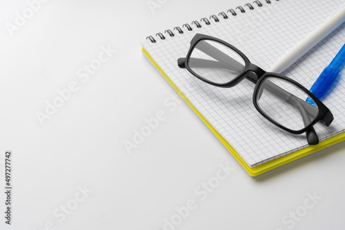Two pens and glasses on open notepad, close up
