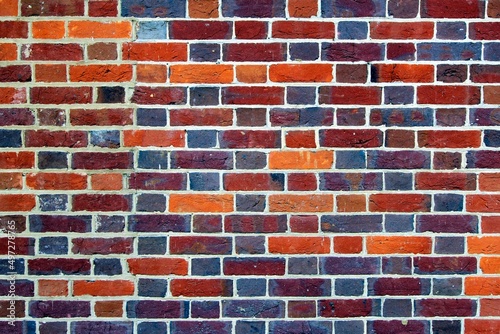 Close up of brick wall, red, orange, blue brickwork pattern.