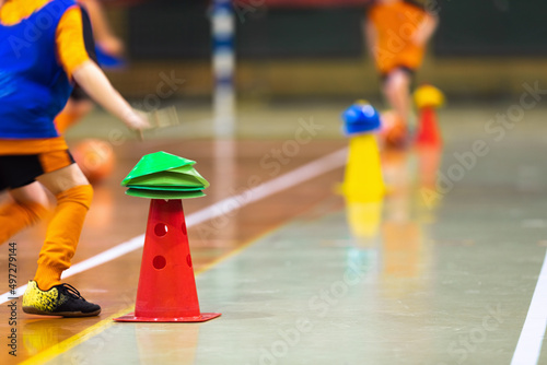 Happy children play indoor sports class. Kids running around training cone during physical education class. Colourful sports training equipment