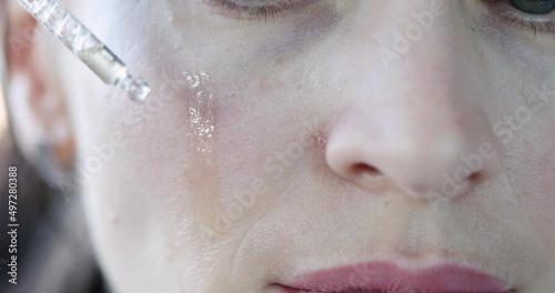 Woman face drop of oil to moisturize skin closeup photo