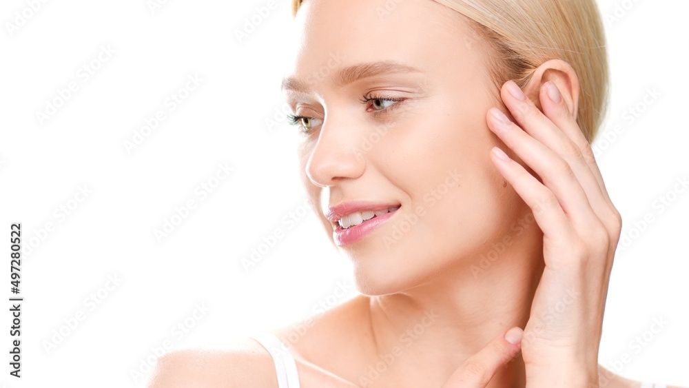 Close-up beauty portrait of young blonde European woman who touches her face turning her head aside on white background | Skin care commercial concept Close-up beauty portrait of young blonde European woman who touches her face turning her head aside on white background | Skin care commercial concept