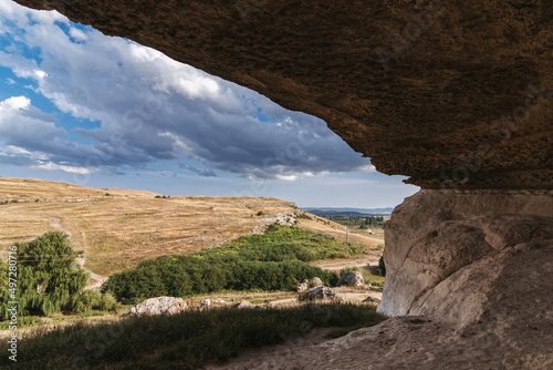 View from a cave in mountains to blue sky on a sunny summer day