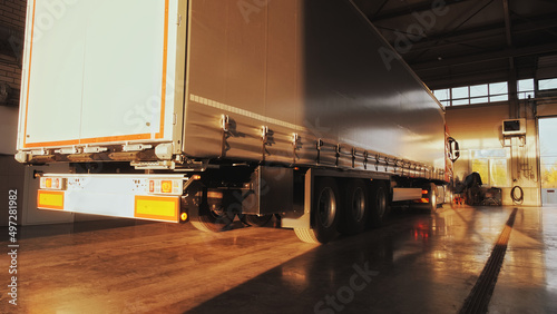 Red truck with cargo trailer pulls into a service station for annual service.