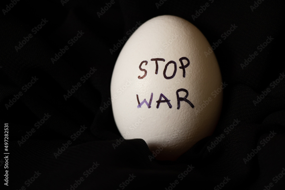 White chicken egg with the inscription stop the war, which lies on a black background, food and war in Ukraine White chicken egg with the inscription stop the war, which lies on a black background, food and war in Ukraine