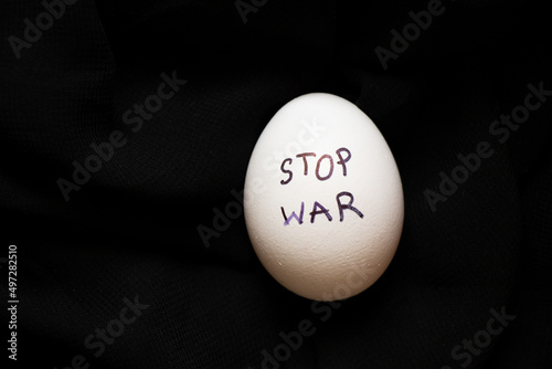 White chicken egg with the inscription stop the war , which lies on a black background, food and war in Ukraine photo