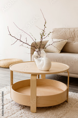 A vase with branches and a ceramic vase on a wooden table in the interior of the room.