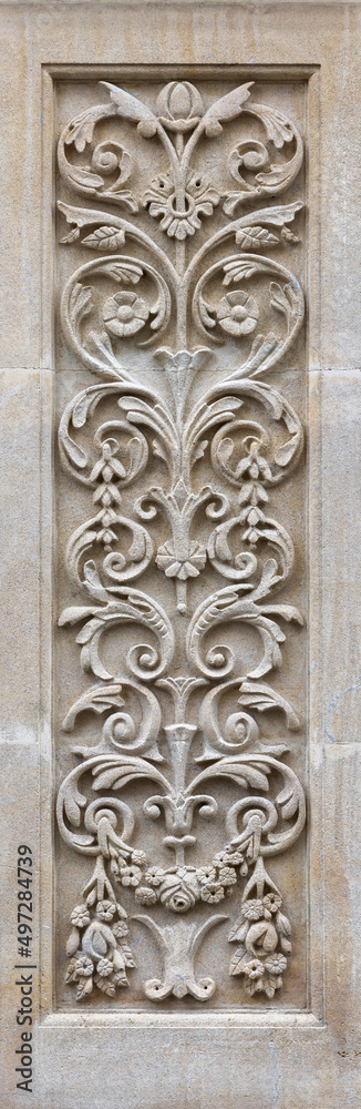 Art nouveau style carved panel on a building exterior. Ornate decorative panel with leaves and flowers.