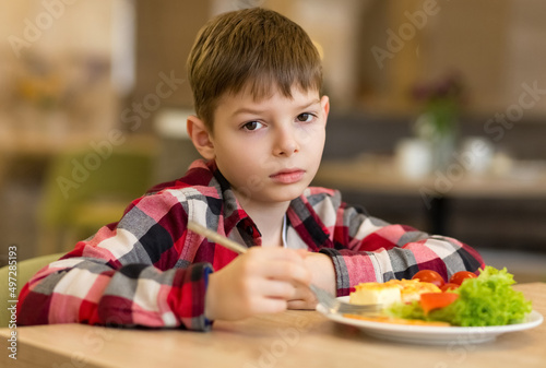Sad boy has a bad appetite at the table. Refusal to eat. The need for proper nutrition.