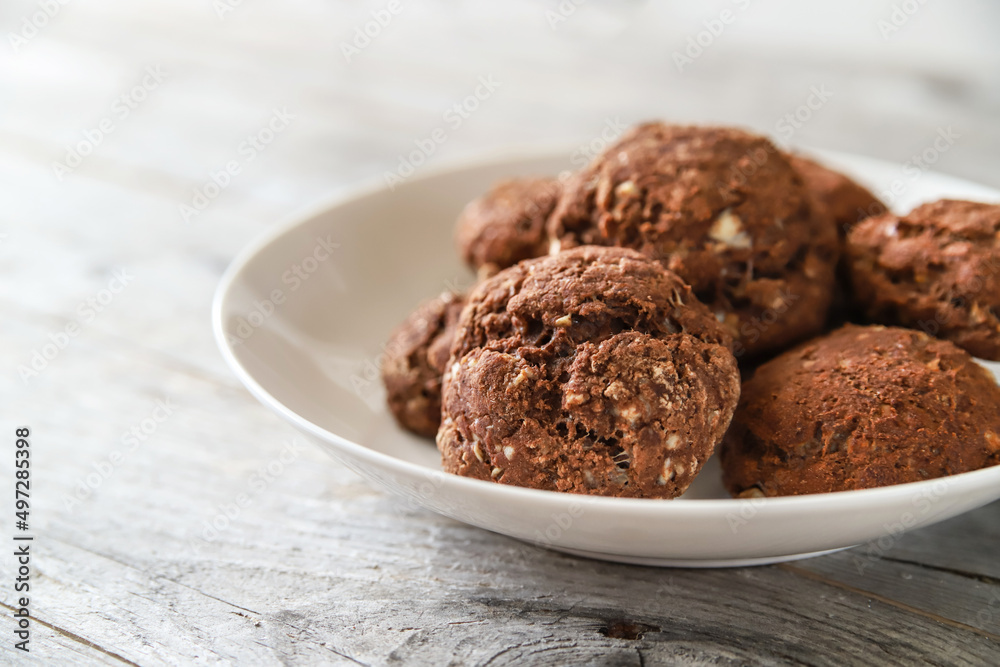 Chocolate cookies with white chocolate chips in a plate on a wooden table, close up. Tasty homemade bakery Chocolate cookies with white chocolate chips in a plate on a wooden table, close up. Tasty homemade bakery