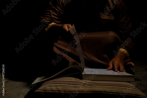 Selective focus picture men turning Quran page in dark mood. Quran hour concept photo